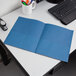 A blue Oxford 2-pocket paper folder on a white desk.