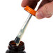 A hand using Elmer's rubber cement to glue a small bottle with a brush.