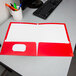 A red Oxford 2-pocket folder on a white desk.