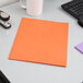 An orange Oxford 2-pocket paper folder on a desk next to a pen.