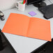 An orange Oxford 2-pocket paper folder on a desk.