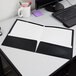 A black Oxford folder on a white desk with a keyboard.