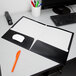 A black Oxford 2-pocket folder on a desk with a piece of paper in it.