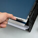 A person using a Pendaflex dark blue desk file with white paper inside.