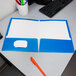 An Oxford blue high gloss laminated paper folder on a desk.