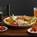 A Choice aluminum tray with chicken wings and dipping sauces on a table with beer glasses.