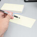 A person holding a pen and writing on an Oxford Ruled Index Card.
