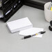 A stack of white Oxford ruled index cards with a pen and a cup on a table.