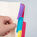A hand holding a Pendaflex file folder with colorful tabs.