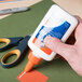 A person using Elmer's Glue-All to glue a piece of paper.
