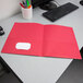 A red Oxford 2-pocket folder sitting on a desk.