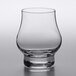 A close-up of a clear Libbey Distill Whiskey Glass with a small amount of liquid in it.