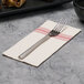A red and white dishtowel print dinner napkin with a fork on top.