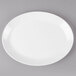 An ivory melamine oval platter with a white rim on a gray surface.