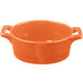 An orange porcelain oval cocotte with handles on a white background.