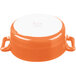 An orange porcelain oval cocotte with white handles.