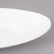 A close-up of a Bon Chef white porcelain plate with a thin rim.