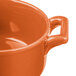 An orange porcelain Bon Chef cocotte with a handle.