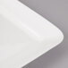 A close-up of a white Bon Chef porcelain square plate with white circles on the rim.