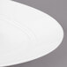 A close up of a white Bon Chef porcelain plate with a slanted oval shape.