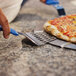 A person using a GI Metal perforated triangular pizza server to cut a pizza.