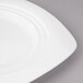 A close-up of a white Bon Chef Concentrics porcelain dinner plate with a curved edge.