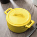A yellow porcelain cocotte with a handle and a fork.