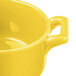 A close-up of a yellow Bon Chef porcelain cocotte with handles.