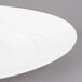 A close-up of a white Bon Chef porcelain plate with a curved rim.