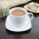 A white porcelain saucer with a cup of coffee and cookies.