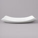 A close up of a white square porcelain plate with a curved edge.