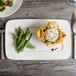 A Bon Chef white porcelain rectangular plate with a pastry and green beans on it.