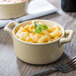 A close up of a Bon Chef wheat porcelain cocotte filled with macaroni and cheese with a fork.