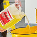 A person pouring yellow Sierra by Noble Chemical liquid into a bucket.