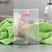 A clear plastic bag with red text containing Noble Chemical Last Rinse Sanitizer packets next to a green towel.