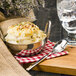 A bowl of mashed potatoes with a Walco 0901 stainless steel spoon on a table.