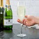 A hand holding a Libbey Contour champagne flute full of champagne.