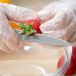 A person in gloves using a Mercer Culinary Praxis paring knife to cut a strawberry.