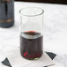 A Libbey Spanish green wine tumbler filled with red wine on a table.