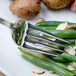 A Walco Pacific Rim European table fork on a plate with green beans and potatoes.