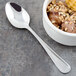 A bowl of ice cream with nuts and a Walco stainless steel dessert spoon.