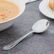 A large bowl of soup with a Walco Meteor bouillon spoon on a table.