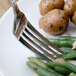 A Walco Meteor stainless steel dinner fork on a plate of green beans and potatoes.