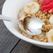 A Walco stainless steel teaspoon in a bowl of oatmeal with bananas and strawberries.