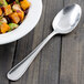 A bowl of salad with a Walco stainless steel serving spoon.