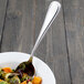 A Walco stainless steel serving spoon in a bowl of food.