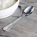 A Walco stainless steel serving spoon in a bowl of rice on a table.