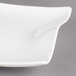 A close-up of a white Villeroy & Boch square porcelain plate with a curved edge.