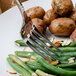 A Walco Meteor stainless steel table fork on a plate of green beans and potatoes.