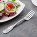 A Walco Saville stainless steel salad fork next to a plate of salad.